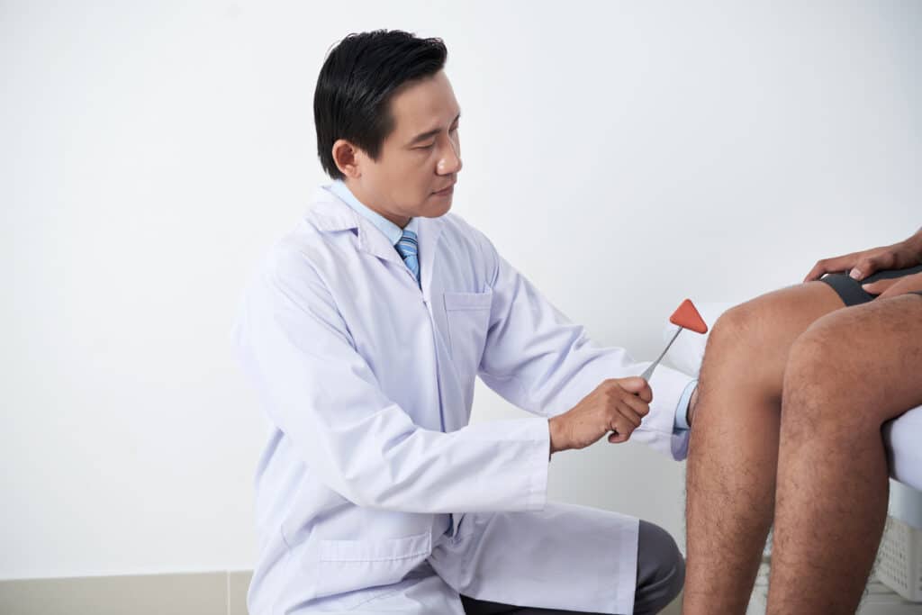 Surgeon examining knee reflex