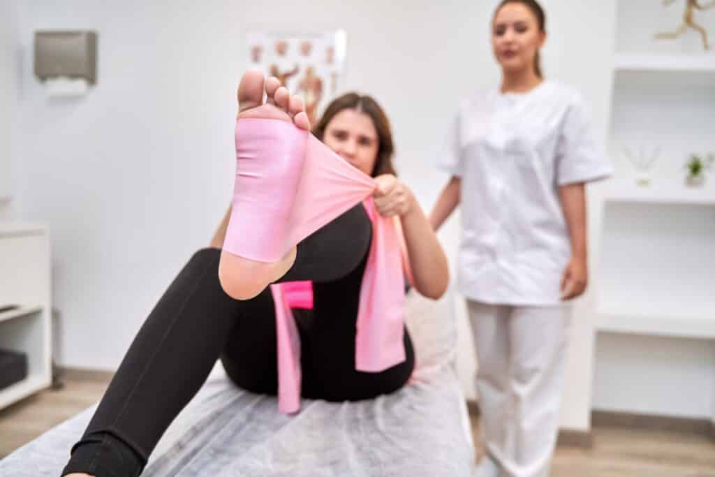 Physiotherapist Observing Female Patient's Leg Exercises with Elastic Bands